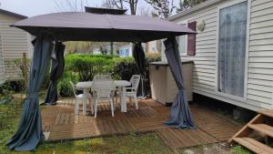 a patio with a table and chairs under an umbrella at Mobile home 4 personnes - La Cotinière - Ile d'Oléron in La Cotinière