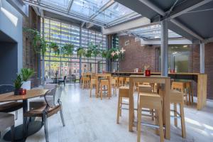 a restaurant with wooden tables and chairs and windows at Leonardo Hotel Breda City Center in Breda