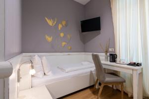 a white bedroom with a desk and a bed and a chair at Best Western Hotel Strasser in Graz