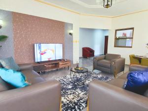 Elegant Appartement BELAPPART في بوانت نوار: غرفة معيشة مع كنب وتلفزيون بشاشة مسطحة