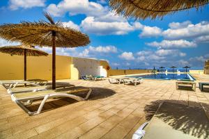 a patio with chairs and umbrellas and a swimming pool at Apartement Zen&Chill Don Franco in Adeje