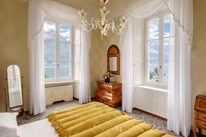 a bedroom with a large bed and two windows at Grand Hotel Villa Serbelloni - A Legendary Hotel in Bellagio