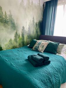 a bedroom with a bed with a forest mural on the wall at Chillout Airport Apartment KL33 - Free parking in Warsaw
