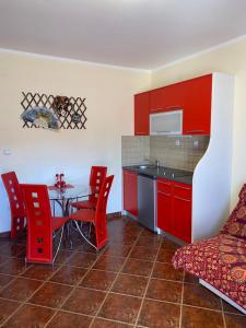 ティヴァトにあるApartments Villa Viktoriaのキッチン(赤いキャビネット、テーブル、赤い椅子付)