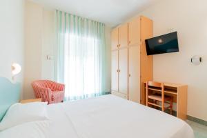 - une chambre avec un lit blanc et une télévision dans l'établissement The Match Hotel, à Cervia
