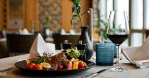 einen Tisch mit einem Teller Essen und einem Glas Wein in der Unterkunft Weinberghotel Edelacker in Freyburg