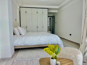 1 dormitorio con cama blanca y mesa en RUYER LUXURY 1BR kileleshwa, en Nairobi