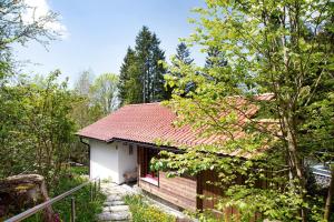 una piccola casa con un tetto rosso nel bosco di Berghütte Waldhäuser a Neuschönau