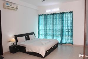 a bedroom with a bed and a window with blue curtains at Niva Stays Marvel 1 in Pune