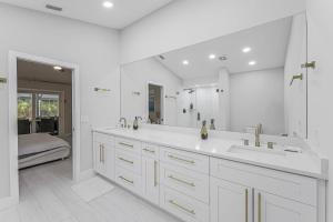 ein weißes Badezimmer mit zwei Waschbecken und einem großen Spiegel in der Unterkunft Lux Family Pool Spa, 2 Private Pickleball Courts, Ping Pong Table, Mini Golf, Close To Beach & Dining Home Sleeps 8 in Naples