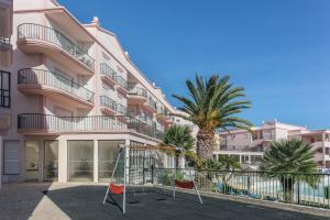 um edifício com uma palmeira e dois baloiços em Luz casas-St James 215, 3 bedrooms,wi fi, air con,shared pool na Praia da Luz