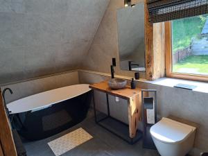 a bathroom with a tub and a toilet and a sink at Domki pod sosnami in Kacwin +17 photos