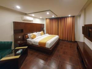 a bedroom with a large bed and a couch at Bling International Hotel Multan in Multan
