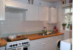 a kitchen with white cabinets and a sink and a stove at Harbour Cottage, Conwy in Conwy