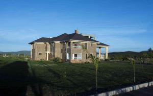 uma grande casa de tijolos num campo de relva em Mara Meguarra Sanctuary em Ololaimutiek