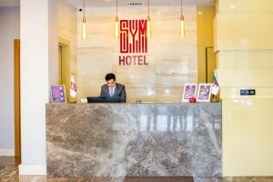 un hombre sentado en una recepción en un hotel en SYM Hôtel en Cheraga