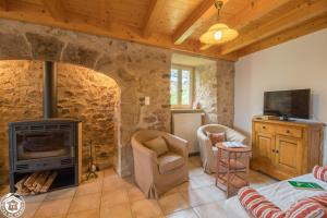 a living room with a stone wall with a fireplace at Goulapie, Village de gîtes in Saint-Quentin-sur-Sauxillanges