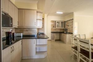 uma cozinha com armários brancos e bancadas pretas em Saints View Resort Unit 17 em Uvongo Beach