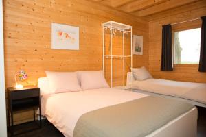 two beds in a room with wooden walls at Recreatiewoning De NieuwenHof in Melderslo