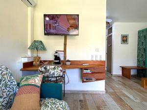 a living room with a couch and a tv on the wall at La Marigalantine - Piscine, Plage, Blue Dream in Grand-Bourg