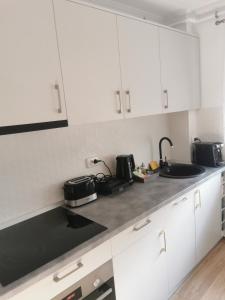a kitchen with white cabinets and a black counter top at Sidus in Satu Mare