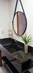 een badkamer met een zwarte wastafel en een spiegel bij Sobrado com 3 Suítes, Piscina, Sala de Jogos, Playground, Garagem para 4 Carros in Florianópolis
