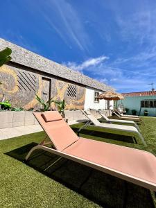 a row of lounge chairs and an umbrella on a lawn at Casas Jeronimos in Lourinhã