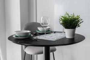uma mesa preta com um copo de vinho e uma planta em CityCenter Sauna & Fitness Apartments Podgórna by Renters Prestige em Poznań