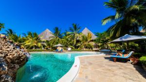 a woman sitting in a chair next to a swimming pool at Tembo Court Apartments(2 Bdrm) in Malindi