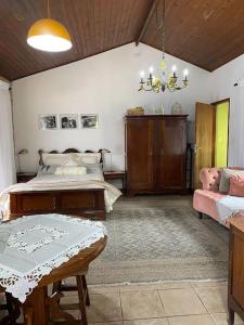 ein Schlafzimmer mit einem Bett, einem Tisch und einer Couch in der Unterkunft Sítio Vale da Colina-Nazaré Paulista - 6 pessoas in Nazaré Paulista