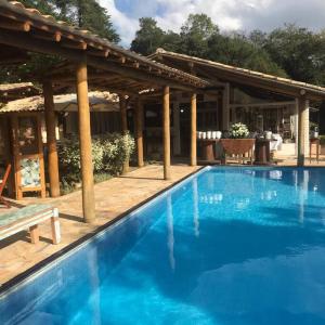 ein großer blauer Swimmingpool neben einem Pavillon in der Unterkunft Sítio Vale da Colina-Nazaré Paulista - 6 pessoas in Nazaré Paulista
