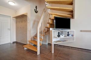 a living room with a staircase with a flat screen tv at Ferienhaus Seepferdchen in Dranske