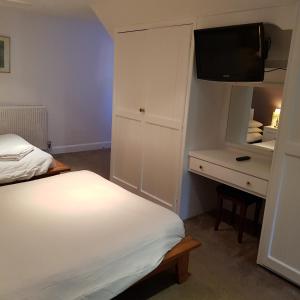 a bedroom with a bed and a dresser with a television at The Grange Hotel in Bury Saint Edmunds