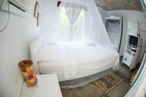 a bedroom with a white bed with a veil at Casa Grande Flats in Abraão