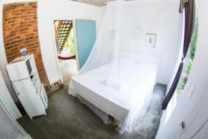 ein weißes Bett in einem Zimmer mit Fenster in der Unterkunft Casa Grande Flats in Abraão