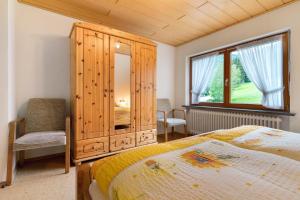 a bedroom with a bed and a cabinet and a window at Sulzerhof in Bad Rippoldsau-Schapbach