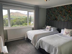 1 dormitorio con 2 camas y ventana con vistas a las montañas en Braeburn Guesthouse, en Fort William