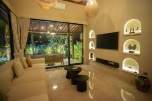een woonkamer met een witte bank en een tv bij Adi Laxmi Villa Ubud in Ubud