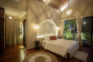 een slaapkamer met een wit bed en een groot raam bij Adi Laxmi Villa Ubud in Ubud