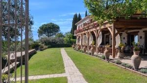 einen Garten mit Blumentopfen und ein Gebäude mit einer Veranda in der Unterkunft La Petite Auberge in Tourtour