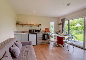uma cozinha e sala de estar com um sofá e uma mesa em Luxury Silver Birch Lodge: Hot Tub/BBQ/Fire Pit em Toppesfield