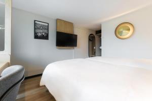 1 dormitorio con 1 cama blanca y TV en Campanile Taverny, en Taverny