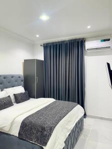 una camera da letto con un grande letto con tende blu di blueocean.cog Apartments a Benin City