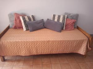 El Racimo, dpto en Ciudad de Mendoza في ميندوزا: سرير عليه عدة وسائد