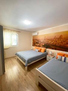 ティヴァトにあるApartments Villa Viktoriaのベッドルーム1室(ベッド2台付)が備わります。壁には絵画が飾られています。