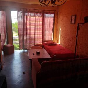 Zimmer mit einem Bett, einem Tisch und Fenstern in der Unterkunft Posada Mar Azul con Jacuzzi in Punta Del Diablo