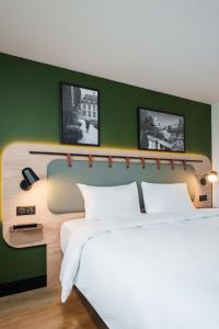 a bedroom with a white bed and a green wall at Campanile Taverny in Taverny