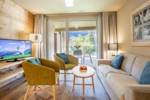 a living room with a couch and chairs and a tv at SWISSPEAK Resorts Meiringen in Meiringen