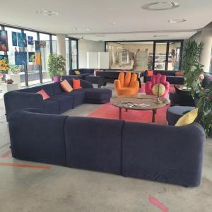 una sala de estar con sofás azules y sillas naranjas. en Auberge de Jeunesse HI Cahors, en Cahors