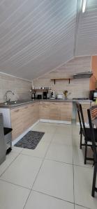cocina con armarios de madera y suelo de baldosa blanca en La Kaz Des Hauts, en Cilaos